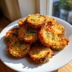 A mound of crispy, golden brown Fried Pickles garnished with fresh dill, served on a white plate.
