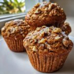 Close-up of freshly baked banana nut muffins topped with chopped walnuts and powdered sugar.