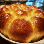 Close-up of a cluster of freshly baked, golden brown dinner rolls glistening with butter.