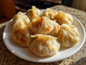 A close-up of several golden-brown, pan-fried Traditional Chinese Dumplings arranged on a white plate.