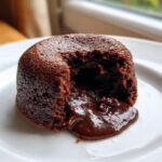 Close-up of a warm chocolate lava cake with a piece broken open revealing the molten chocolate center.