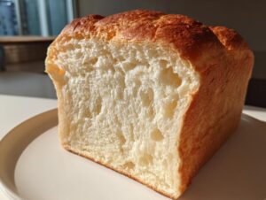 Close-up of a freshly baked milk bread loaf showing its incredibly soft, fluffy white crumb and golden crust.