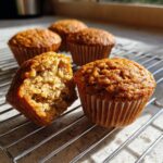 Close-up of moist banana oatmeal muffins cooling, one broken open to show the texture.