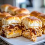 Two halves of delicious bbq chicken sliders showing shredded chicken, melted cheese, and BBQ sauce on soft rolls.