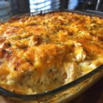 Close-up of a baked chicken cauliflower rice casserole with a bubbly, golden-brown cheese topping and visible shredded chicken.