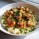 Close-up of chicken scampi pieces served over creamy garlic parmesan rice, topped with fresh parsley.