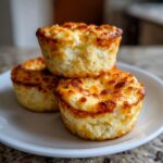 Three golden brown cottage cheese egg cups stacked on a white plate, inspired by Starbucks recipes.