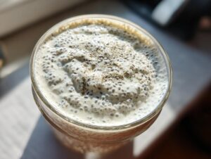 Overhead view of creamy coconut chia pudding in a glass jar, topped with a sprinkle of spice.