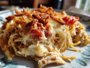 A close-up serving of creamy monterey chicken spaghetti topped with melted cheese, tomatoes, and crispy onions.