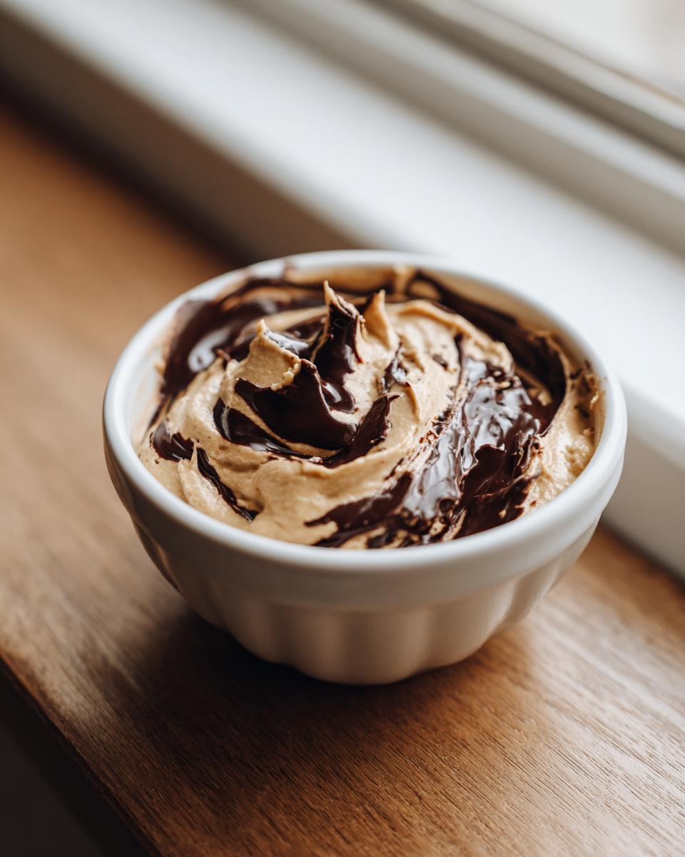 Close-up of a small white bowl filled with creamy peanut butter dip swirled with melted dark chocolate.