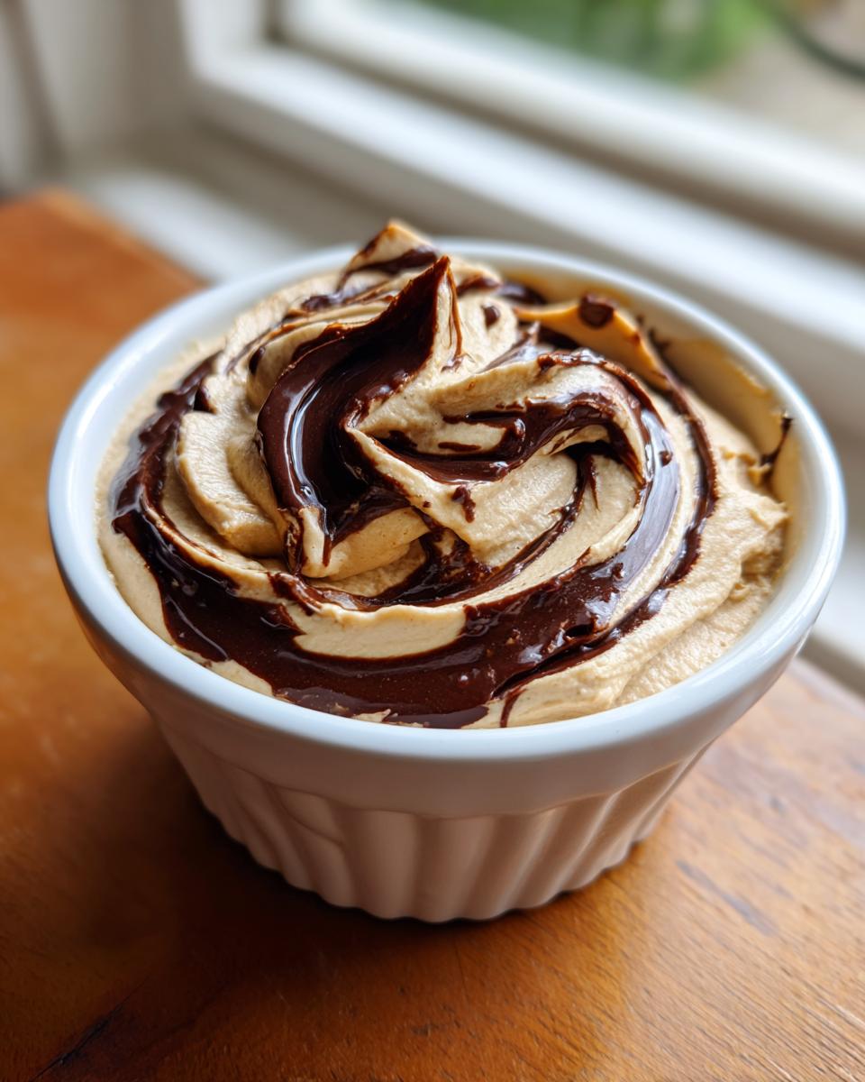 A close-up of creamy peanut butter dip swirled with rich chocolate sauce in a white ramekin.