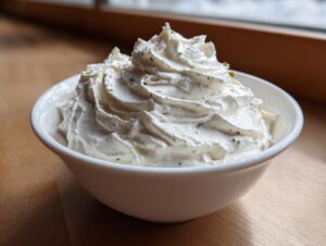 Close-up of perfectly piped, creamy clam dip with visible herbs in a white serving bowl.