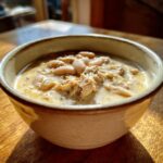 Close-up of a creamy white chicken chili with shredded chicken and white beans in a ceramic bowl.