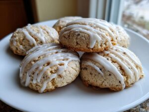 A stack of five freshly baked earl grey cookies drizzled with white vanilla icing on a white plate.