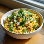 Close-up of creamy, seasoned corn topped with cotija cheese and cilantro, perfect for a street corn chicken rice bowl.