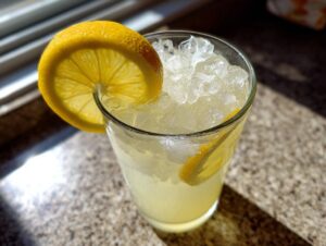 Close-up of a glass filled with crushed ice and homemade lemonade, garnished with a bright lemon slice.