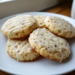 A stack of five homemade earl grey cookies, drizzled with white glaze, resting on a white plate.