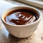 Close-up of thick, rich homemade brown gravy served in a small white ceramic ramekin.