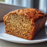 Close-up of a thick slice of moist banana bread recipe loaf showing its rich brown crust and tender crumb.