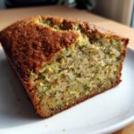 Close-up of a moist slice of zucchini banana bread showing shredded zucchini throughout the crumb.