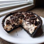 A close-up of a delicious no bake oreo pie with a slice removed, showing the creamy filling and dark crust.