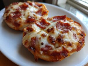 Close-up of two freshly baked pepperoni english muffin pizza halves on a white plate, featuring bubbly, browned cheese.