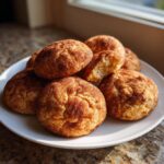 A stack of freshly baked, soft snickerdoodles cookies coated in cinnamon sugar on a white plate.