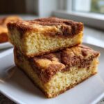Close-up of two stacked, thick snickerdoodle blondies featuring a visible cinnamon swirl texture.