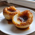 Two halves of perfectly baked pears, cored and filled with caramelized syrup and coated in brown sugar.